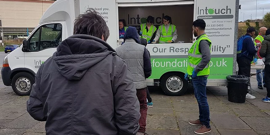 Volunteers serving food in a food-truck to those in need